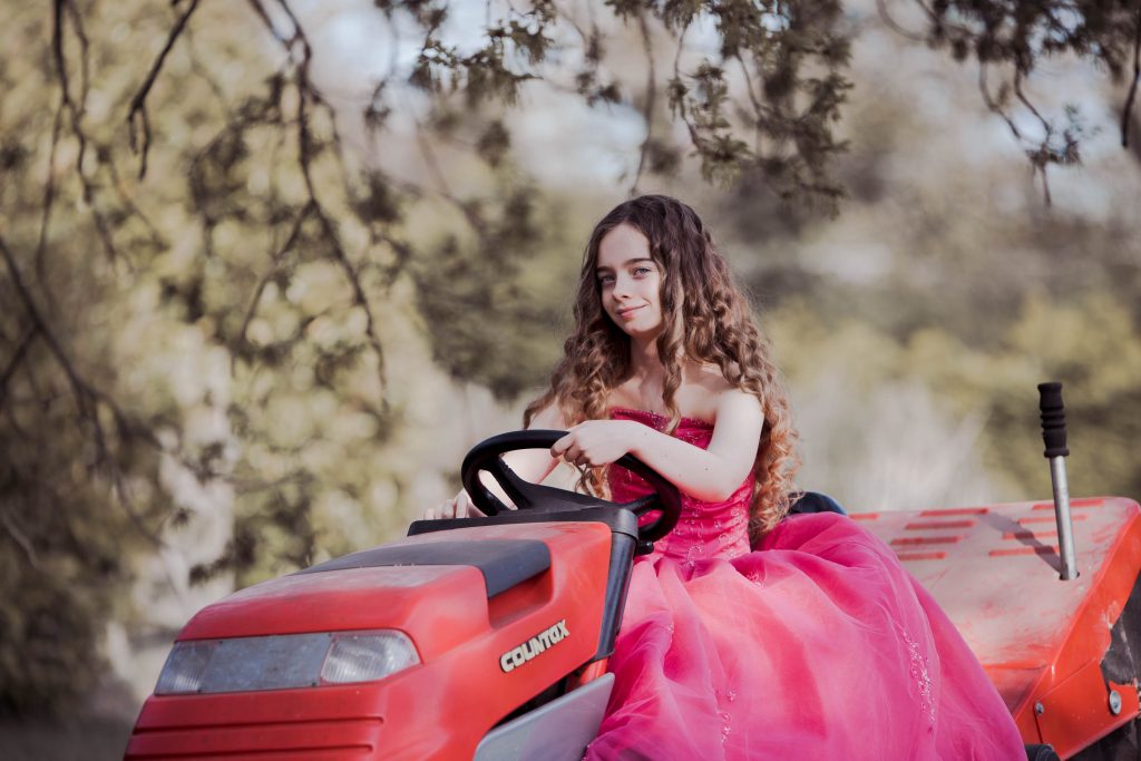 Girl wearing a pink prom dress photographed doing the gardening